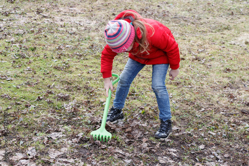 girl cleans fallen leaves in the park in spring