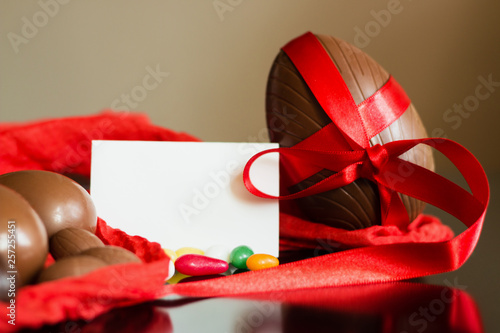 Big and small chocolate Easter eggsde corated with red ribbon photo