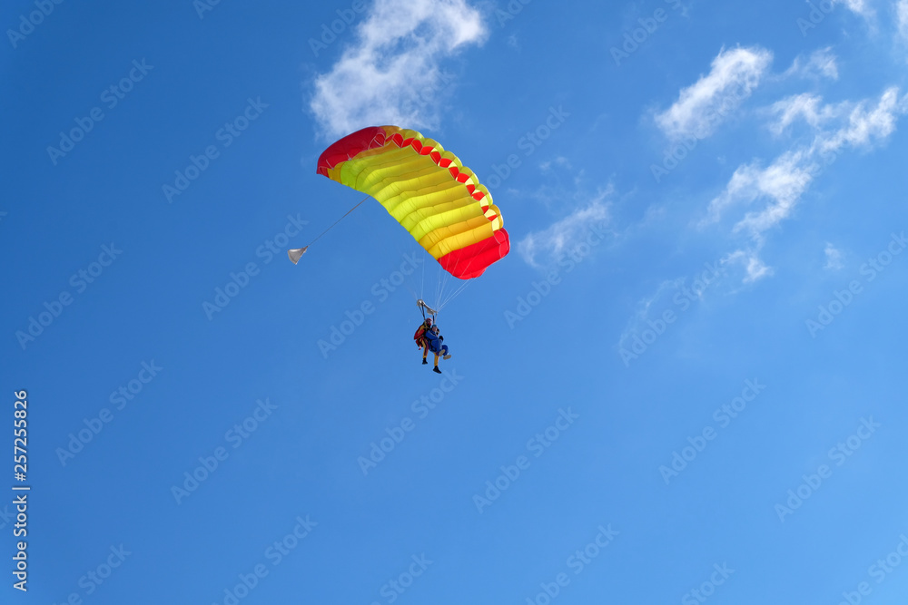 A parachute is in the blue sky. A parachute is in the blue sky.