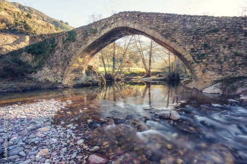 Ancient stone bridge over flowing river in Corsica