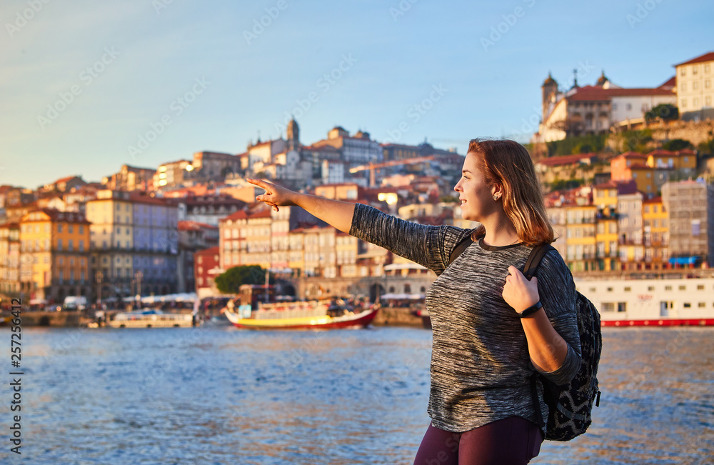 Obraz Young woman tourist enjoying beautiful landscape view on the old town (Ribeira historical quarter) and river Duoro during the sunset in Porto city, Portugal