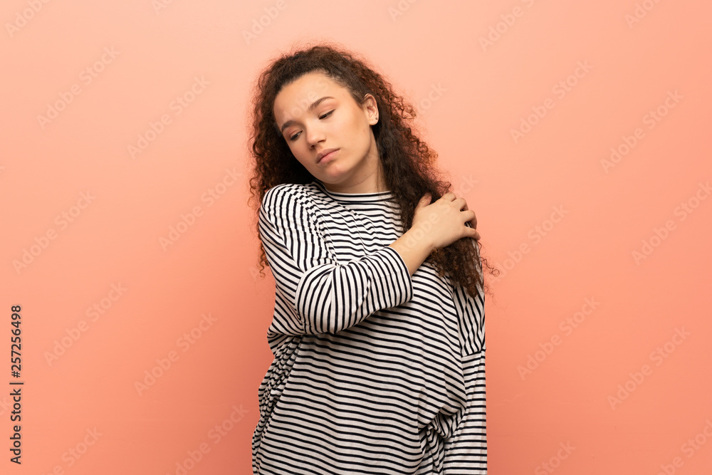 Teenager girl over pink wall suffering from pain in shoulder for having made an effort Teenager girl over pink wall suffering from pain in shoulder for having made an effort