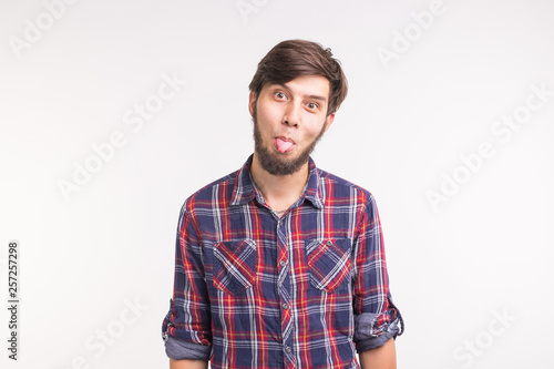 Expression and gesture concept -Young man sticks his tongue out isolated on white background