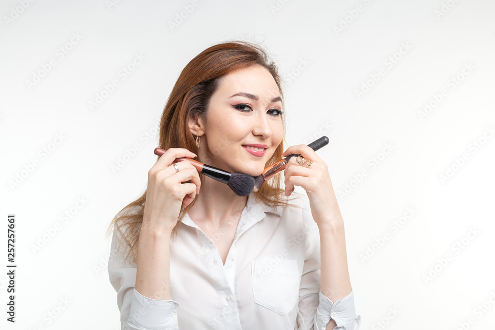 Attractive visagist or korean make-up artist holding a makeup brushes on white background Attractive visagist or korean make-up artist holding a makeup brushes on white background