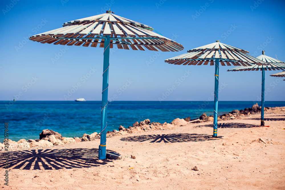 Sun umbrellas on a beach with sea background. Summer and vacation concept