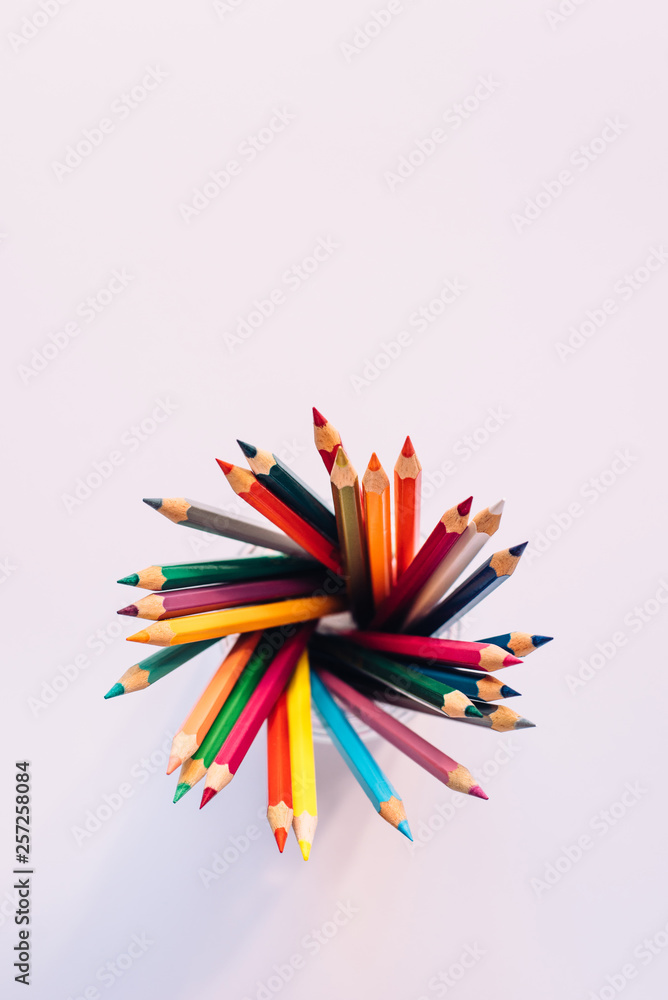 Colored pencils in a glass on a white background. The view from the top. Copy space