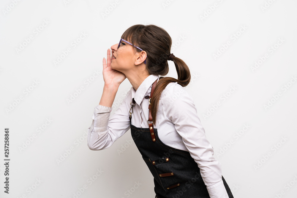 Young woman with apron shouting with mouth wide open to the lateral Young woman with apron shouting with mouth wide open to the lateral