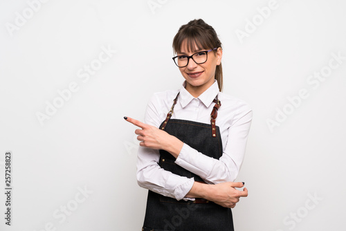 Young woman with apron pointing to the side to present a product