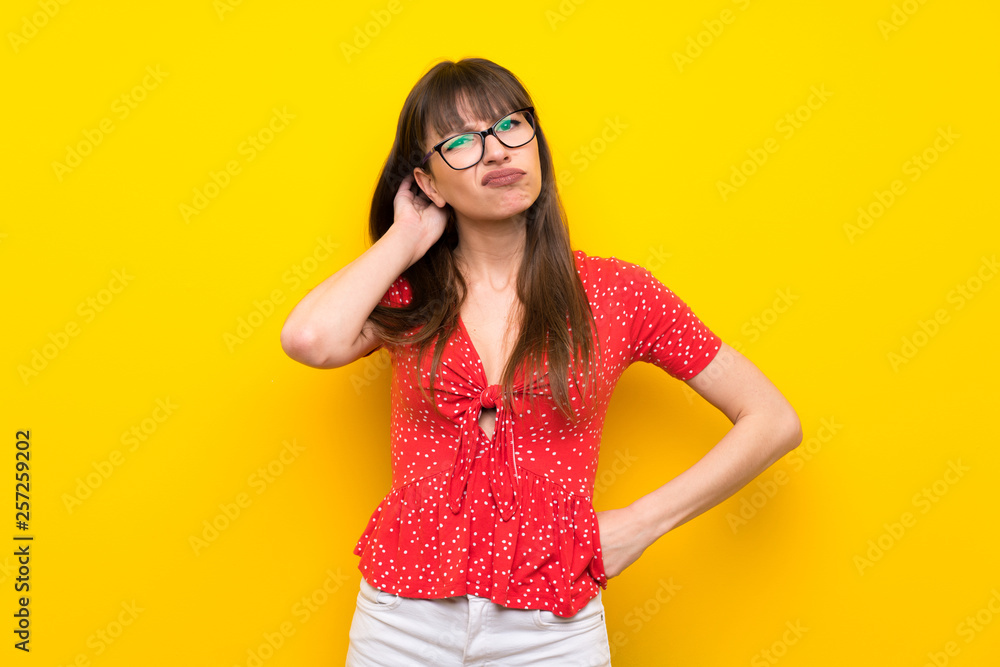 Young woman over yellow wall having doubts Young woman over yellow wall having doubts