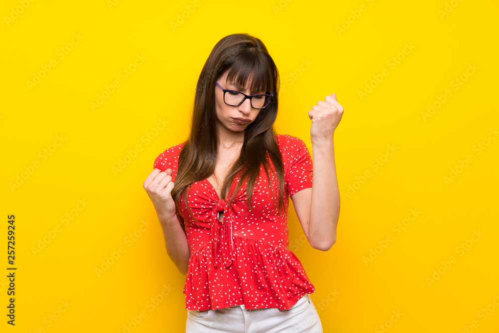 Young woman over yellow wall celebrating a victory Young woman over yellow wall celebrating a victory