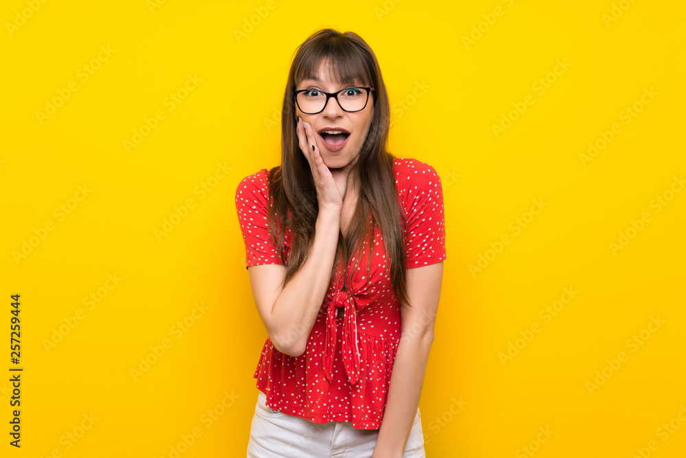 Young woman over yellow wall with surprise and shocked facial expression Young woman over yellow wall with surprise and shocked facial expression