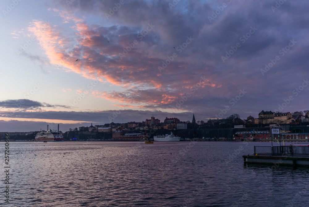 A red, colorful sunrise on the sea in the harbor of  Stockholm in winter  with the backdrop of the Old Town with the sign 
