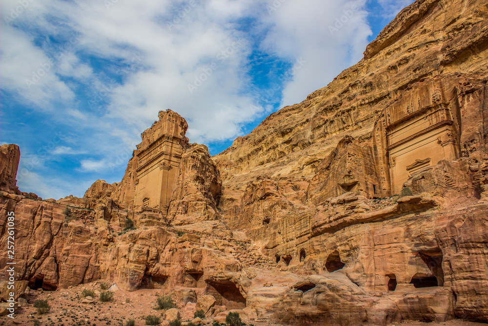picturesque sandstone Middle East rocks from below on vivid blue sky background and ancient temple building carved in yellow stone Petra famous heritage touristic and archeological site 