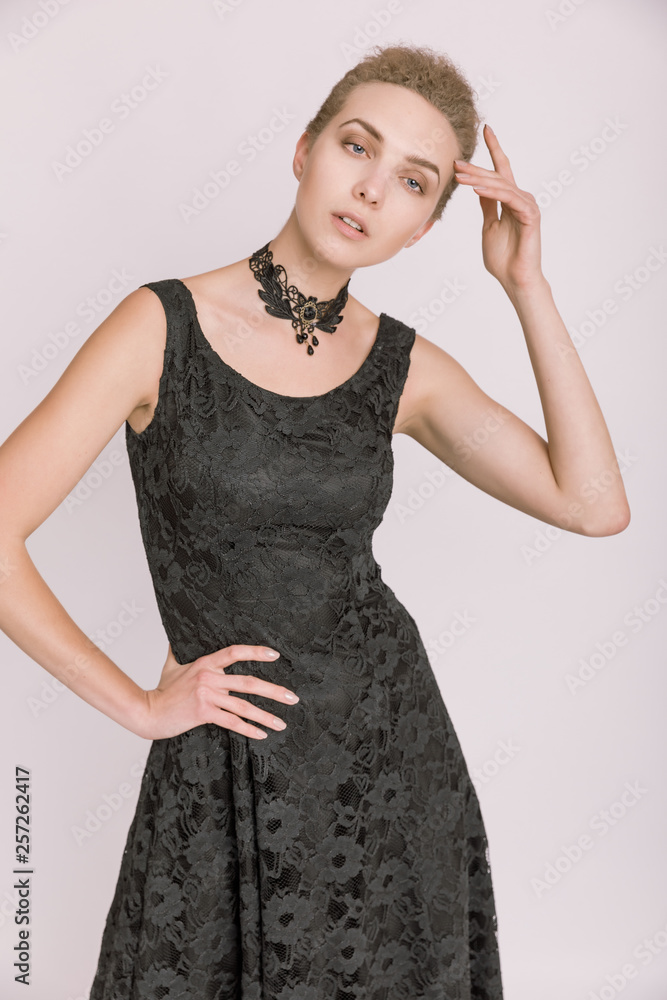 Fototapeta premium Portrait einer jungen Frau in schwarzem Kleid vor hellem Hintergrund