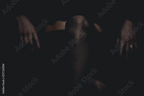 slim sexy woman in black stockings sits on a chair on a black background photo
