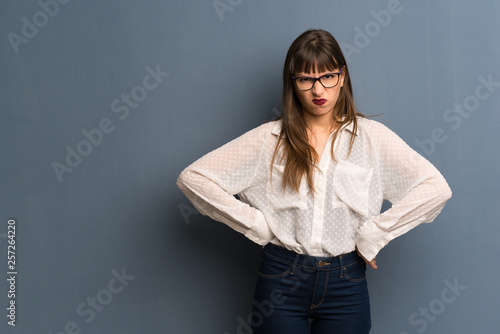 Woman with glasses over blue wall angry