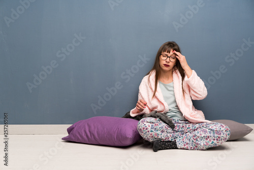 Woman in pajamas on the floor with headache © luismolinero
