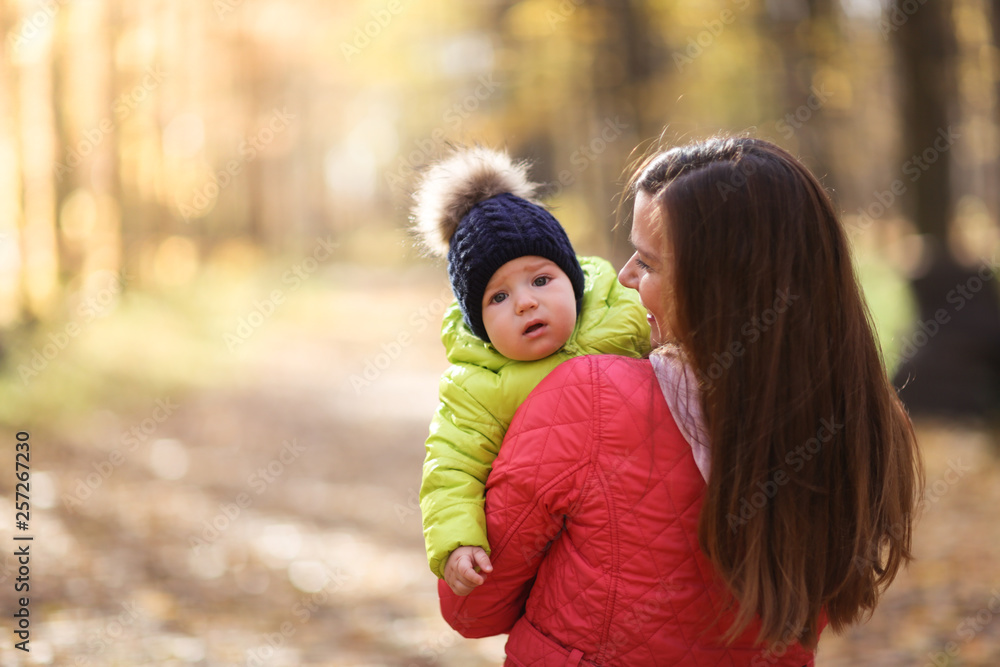 Beautiful brunette mom is holding baby,autumn park Beautiful brunette mom is holding baby,autumn park