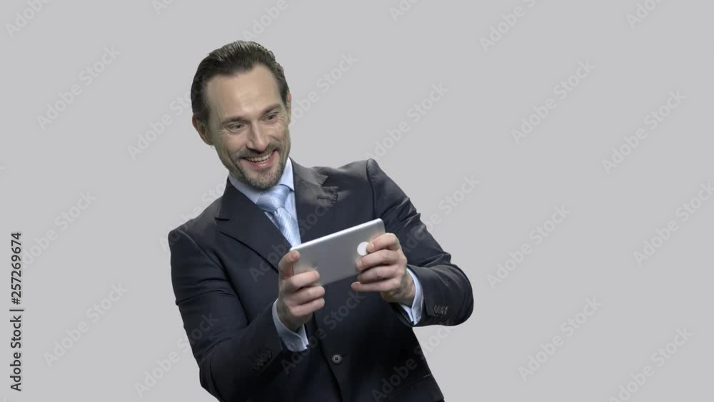 Handsome businessman enjoying game on his smartphone. Excited office man winning game on mobile phone. Man playing game at work. Handsome businessman enjoying game on his smartphone. Excited office man winning game on mobile phone. Man playing game at work.