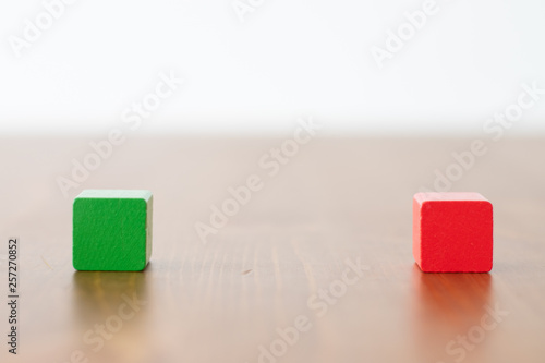Green and red wooden cube on a wooden table 