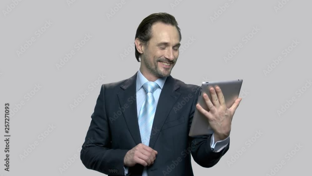Cheerful businessman talking on tablet computer. Businessman using app to have video conference conversation. Entrepreneur having video chat with his wife. Cheerful businessman talking on tablet computer. Businessman using app to have video conference conversation. Entrepreneur having video chat with his wife.