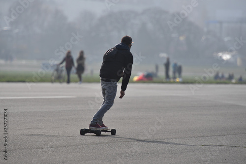 A young man on an electric skateboard drives on the airport runway of the airport Berlin-Tempelhof. photo