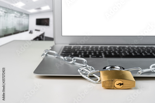 Padlock and chain with laptop computer in a presentation board office room. Cyber security abstract concept.