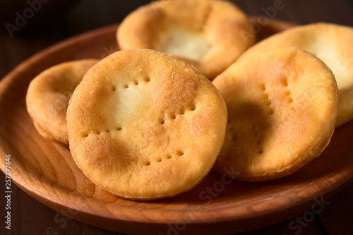 Traditional Chilean Sopaipilla fried pastries made of a bread-like leavened dough served on wooden plate, photographed with natural light (Selective Focus, Focus in the middle of the first sopaipilla) photo