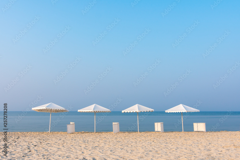 White beach umbrellas on sea background. Sandy beach in the summer.