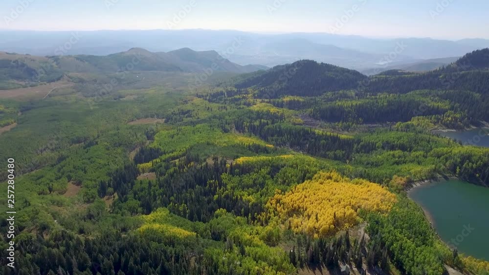 aerial shot of mountain landscape with trees changing yellow secluded lake. The drone slowly gains in height as this beautiful mountain vista is widened. You can see autumn trees with a mountain lake aerial shot of mountain landscape with trees changing yellow secluded lake. The drone slowly gains in height as this beautiful mountain vista is widened. You can see autumn trees with a mountain lake