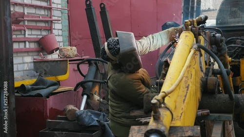 professonal welder working with a yellow metal part of combine