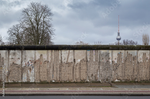 Wallpaper Mural Front view of a section of the original Berlin Wall at the Berlin Wall Memorial (Berliner Mauer) in Berlin, Germany, on a cloudy day. Fernsehturm TV Tower is in the background. Torontodigital.ca