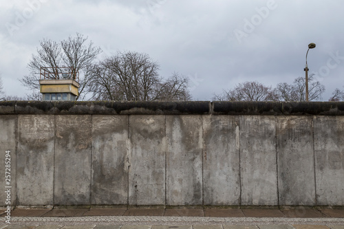 Canvas Print Front view of a section of the original Berlin Wall and watchtower at the Berlin Wall Memorial (Berliner Mauer) in Berlin, Germany, on a cloudy day