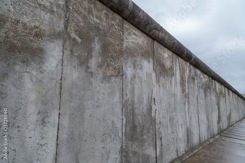 Side view of a section of the original Berlin Wall at the Berlin Wall Memorial (Berliner Mauer) in Berlin, Germany, on a cloudy day.
