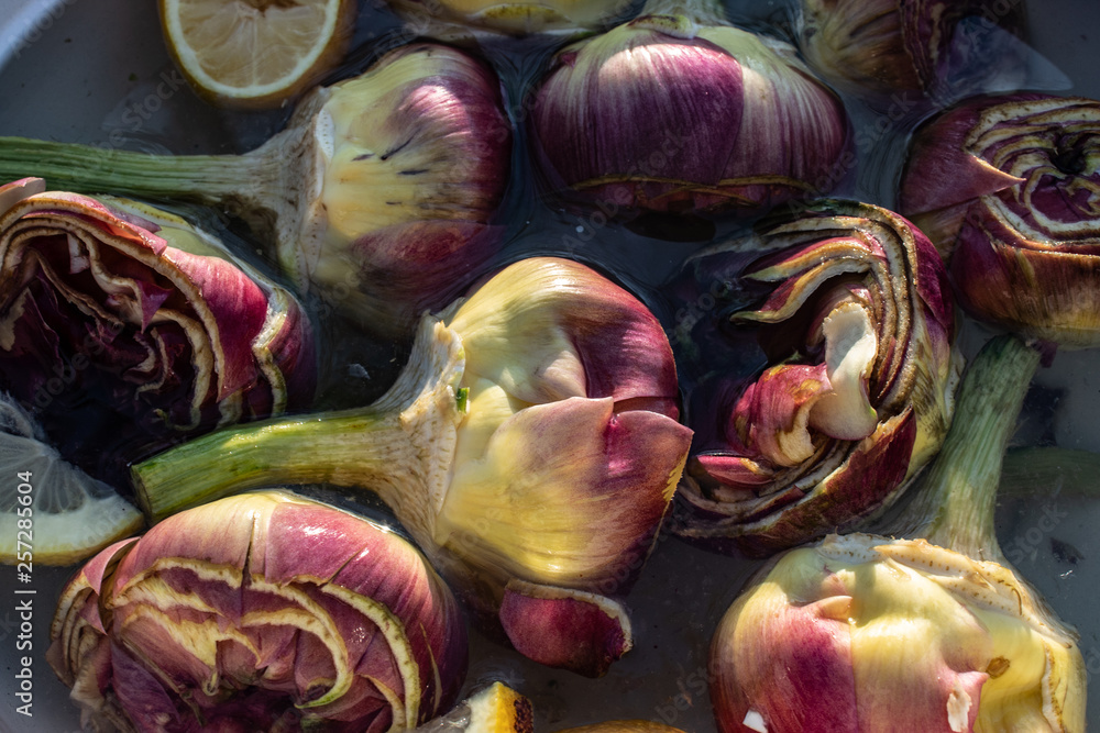 Obraz premium Beautiful italian artichokes, (mammole), freshly cleaned and cut and put in water and lemon, ready to be cooked.