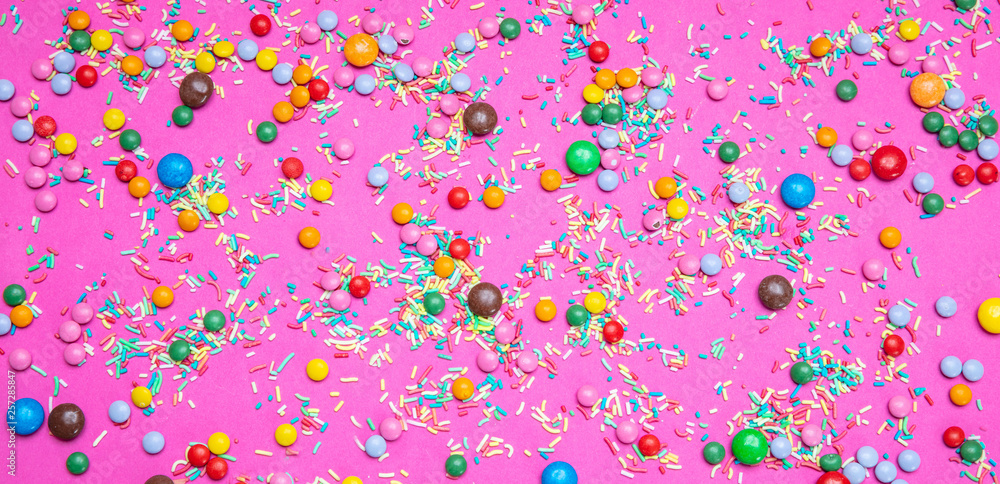 Birthday concept. Colorful sprinkles and candies on bright pink background