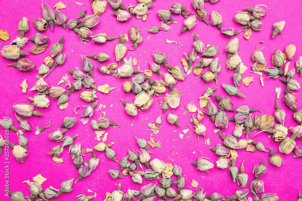 Dried rosebuds against bright pink background, top view.