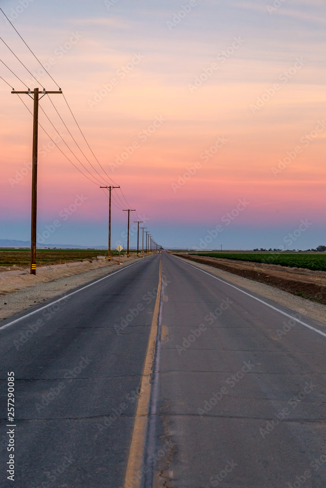 Looking down a long, straight road at sunset Looking down a long, straight road at sunset