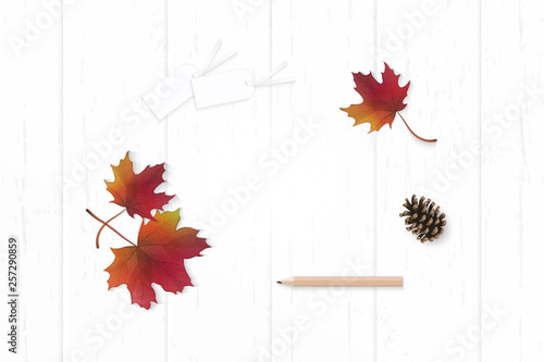 Flat lay top view elegant white composition paper red autumn maple leaf pine cone and pencil tag on wooden background