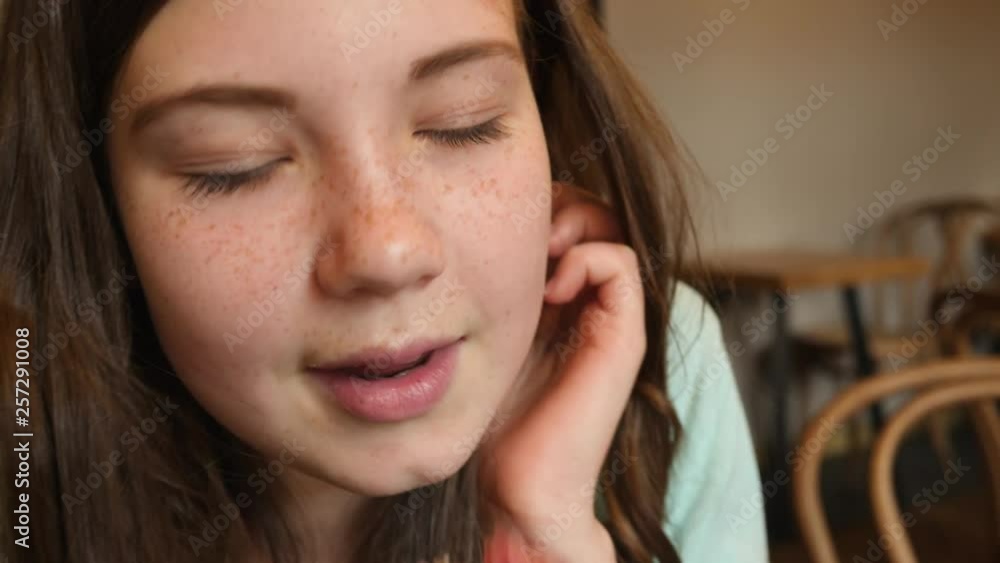 Closeup cute kid girl face portrait while eating piece of cake in a cafe during celebrating birthday party Closeup cute kid girl face portrait while eating piece of cake in a cafe during celebrating birthday party