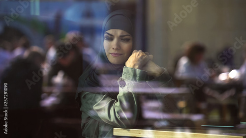 Unhappy woman in hijab sitting in cafe, thinking of problem, big city loneliness