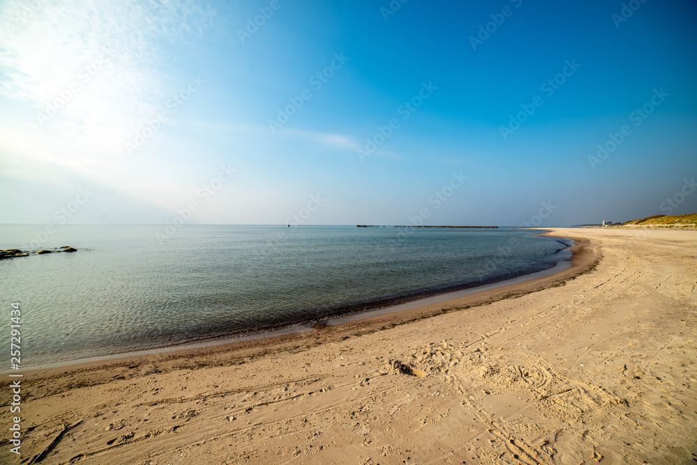 calm sea beach in summer with large rocks and wooden poles from old breakewater in the sea calm sea beach in summer with large rocks and wooden poles from old breakewater in the sea