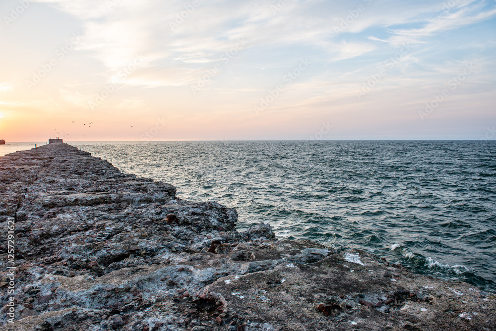 calm sea beach in summer with large rocks and wooden poles from old breakewater in the sea calm sea beach in summer with large rocks and wooden poles from old breakewater in the sea