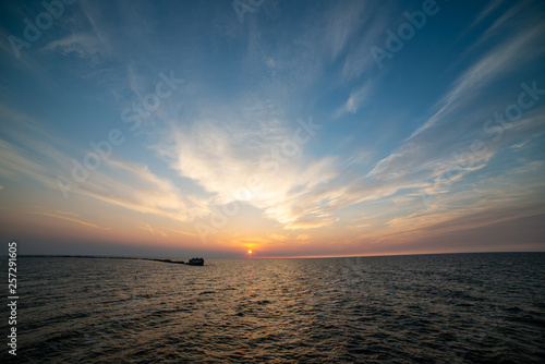 calm sea beach in summer with large rocks and wooden poles from old breakewater in the sea photo