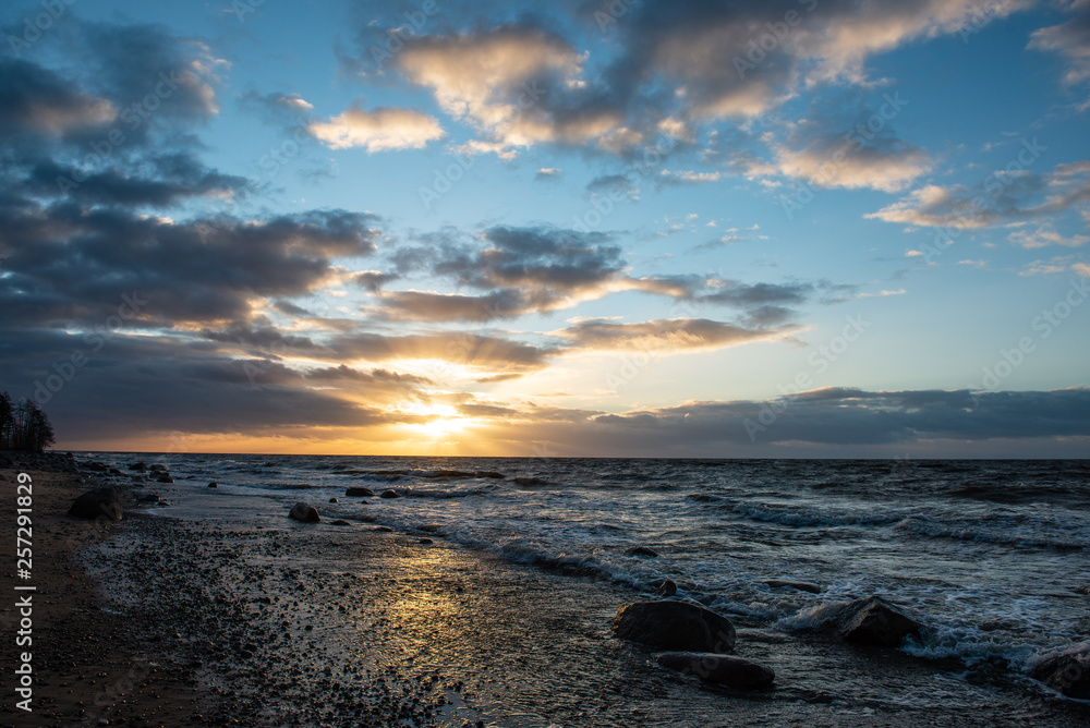 dramatic sunset over sea beach with rocks and stormy water dramatic sunset over sea beach with rocks and stormy water