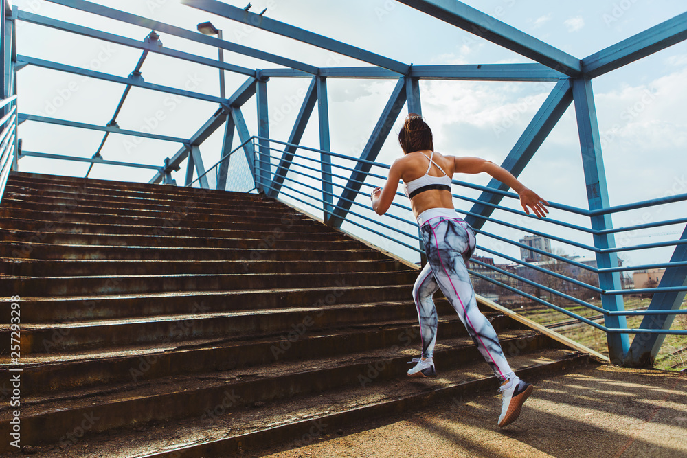 Sporty woman who is running in an urban setting over a bridge