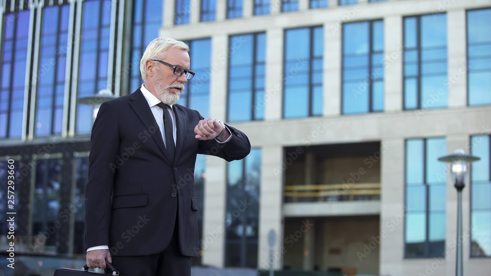 Fototapeta premium Mature company director looking at watch, punctual businessman waiting colleague