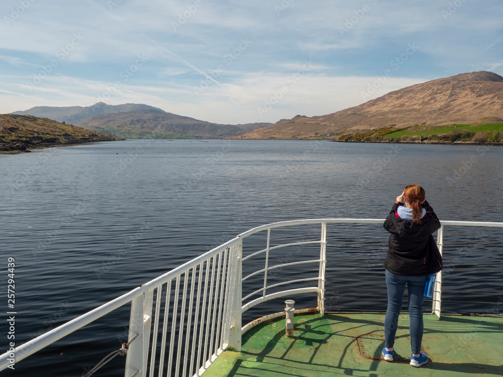 Woman taking pictures on her smart-phone during her trip, Killary fjord, county Galwy. Ireland.