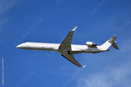 White airplane flying, blue sky in background