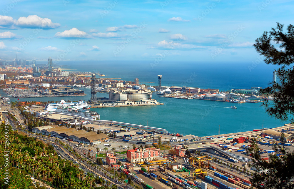 Barcelona, Catalonia, Spain. Top view at sea bay with trading port from hill Monjuic in Barcelona city. Summer sunny day with blue sky and clouds.